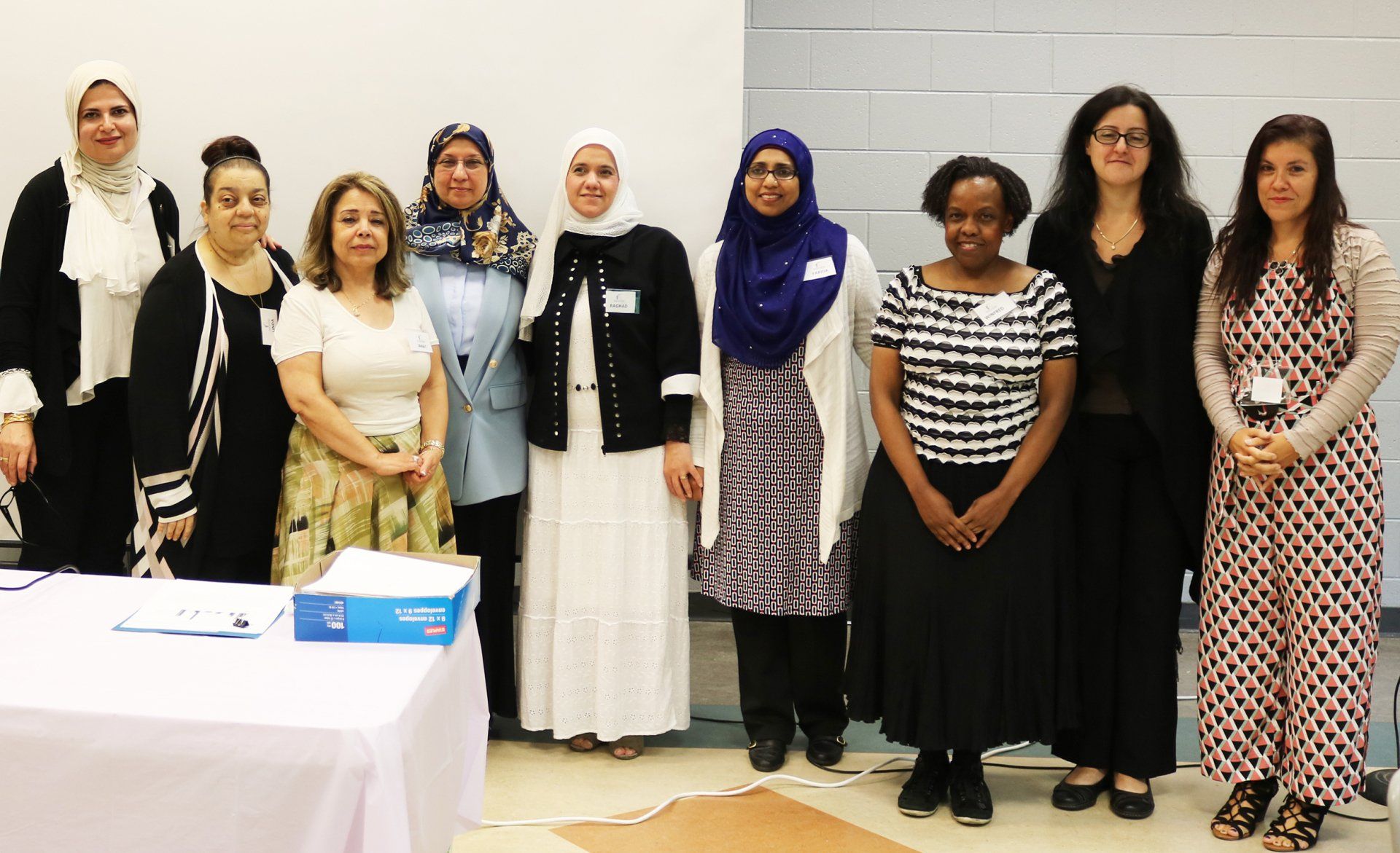 A group of women are posing for a picture in front of a table.