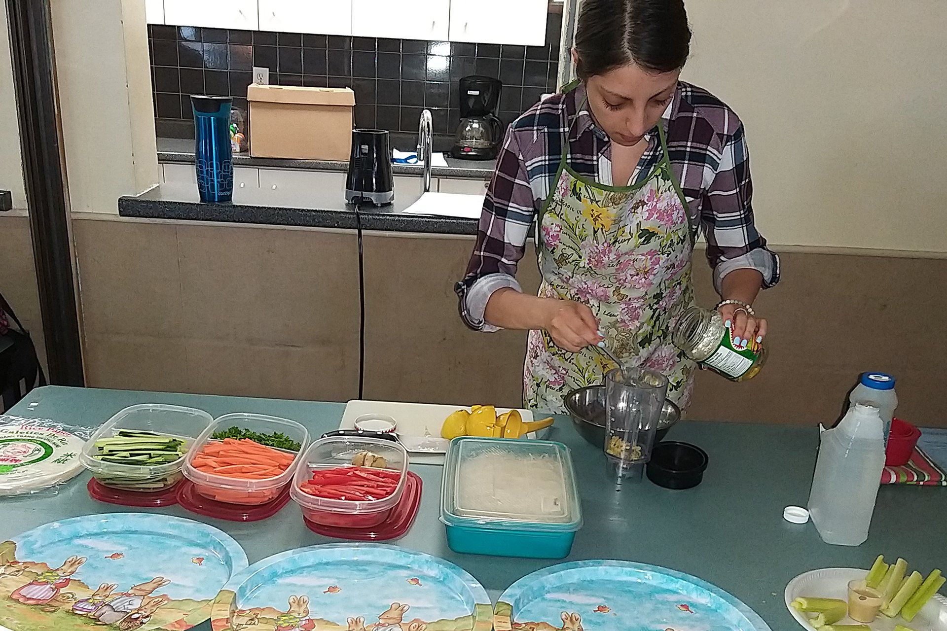 A woman is preparing food on a table in a kitchen.