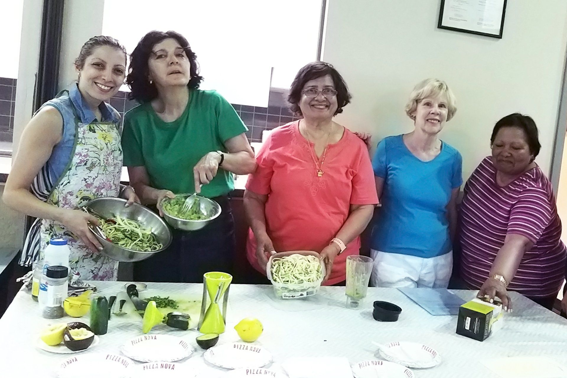 A group of women standing around a table with bowls of food