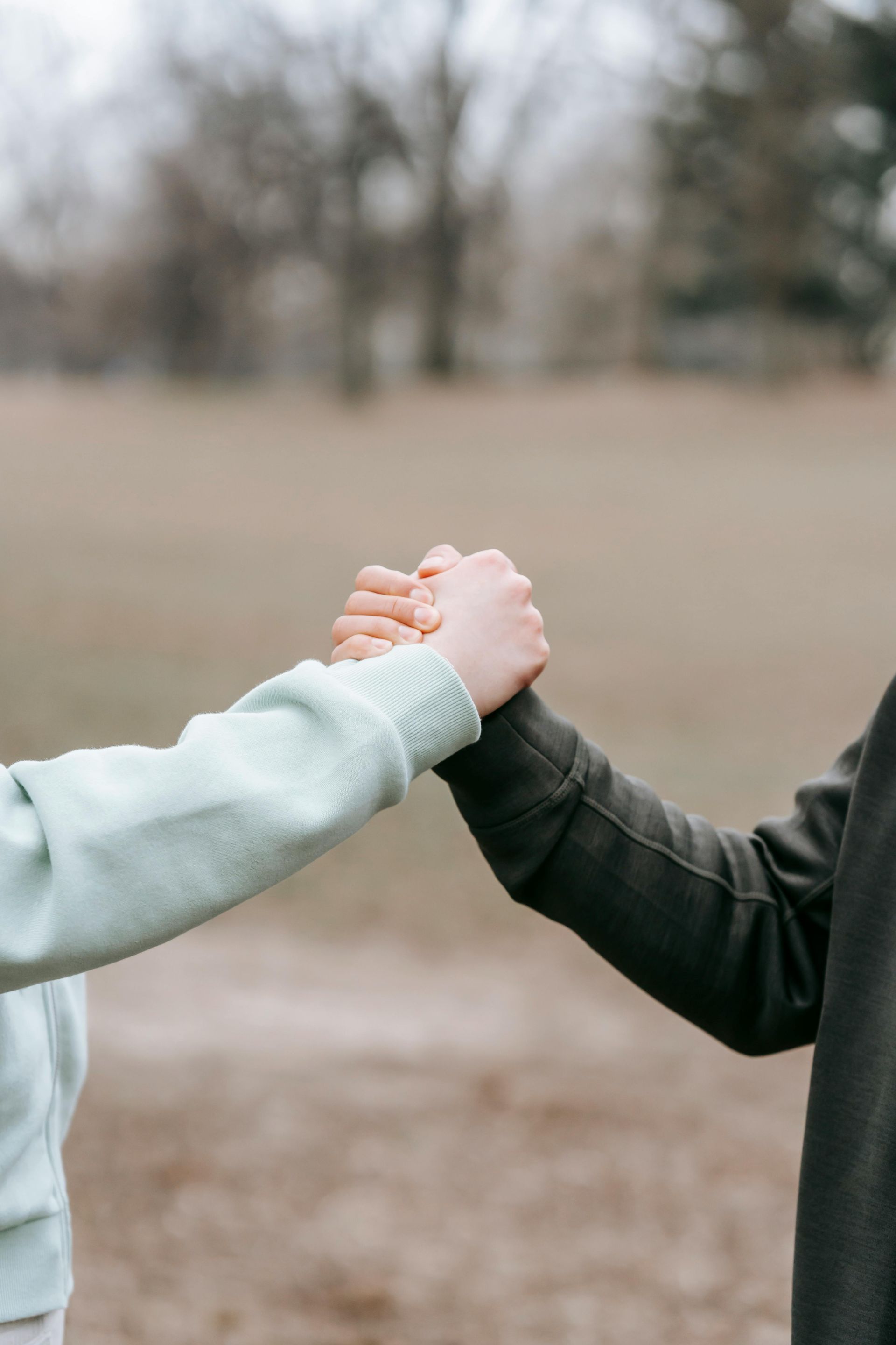 A man and a woman are holding hands in a park.