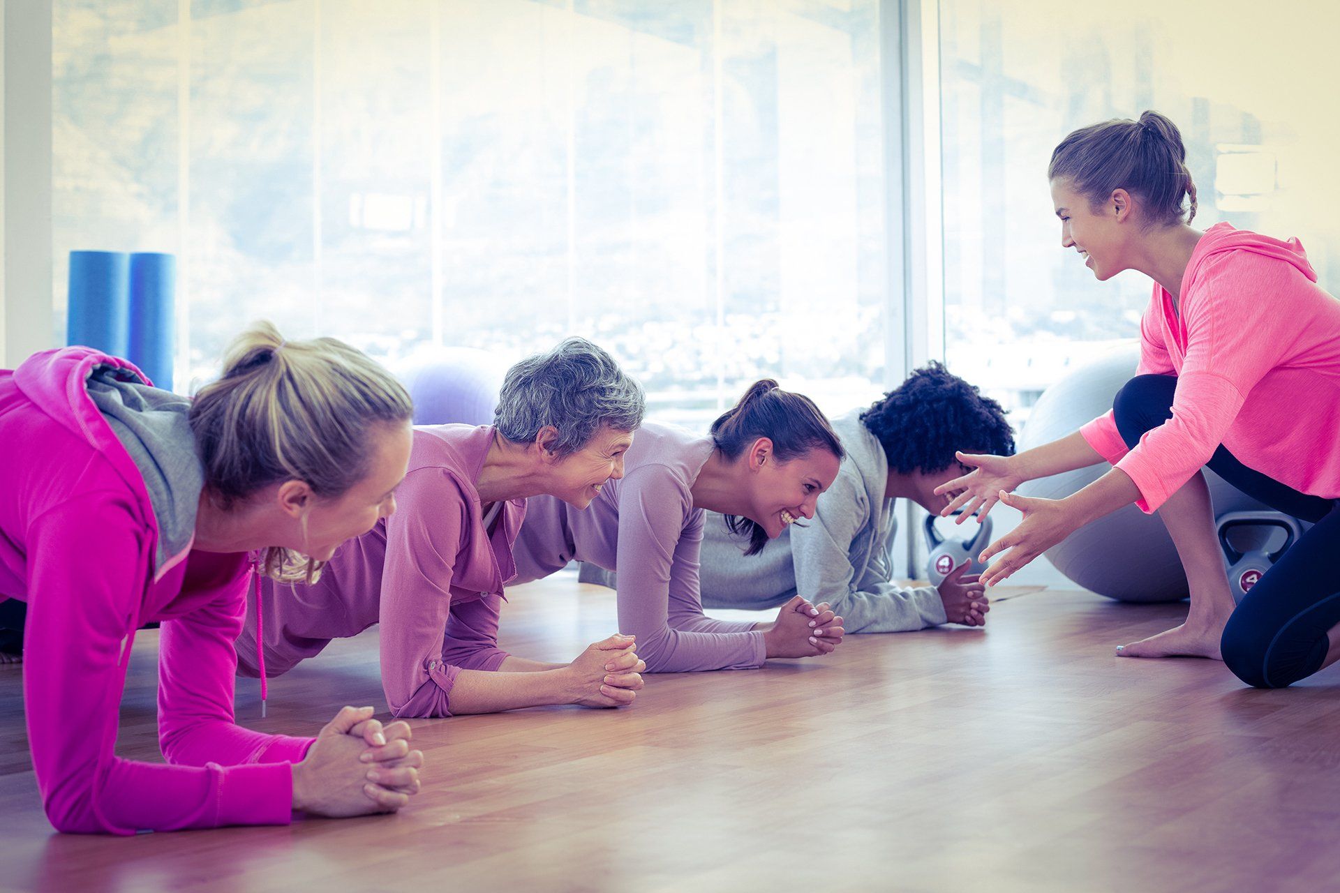 A group of women are doing plank exercises in a gym.