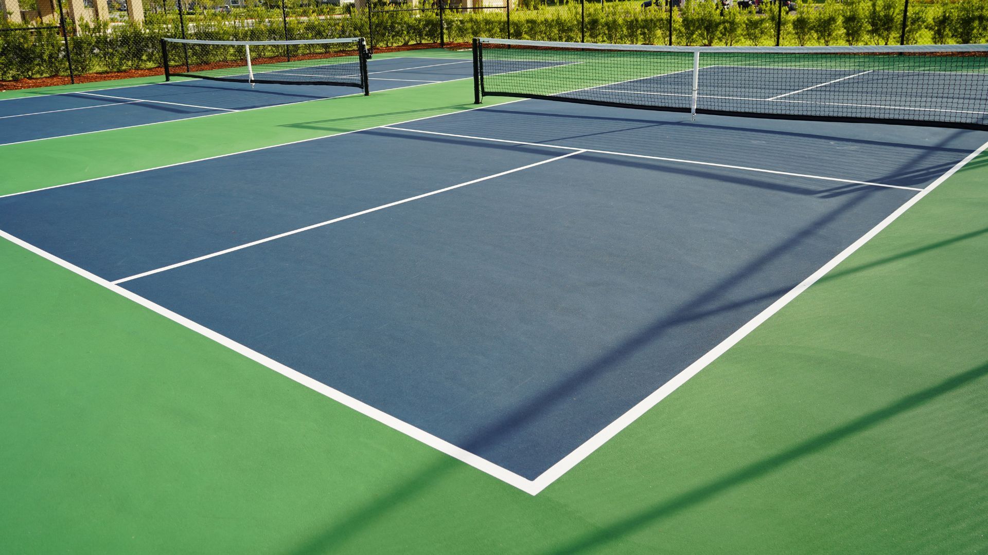 Empty tennis court with a green and blue surface and a net in the foreground