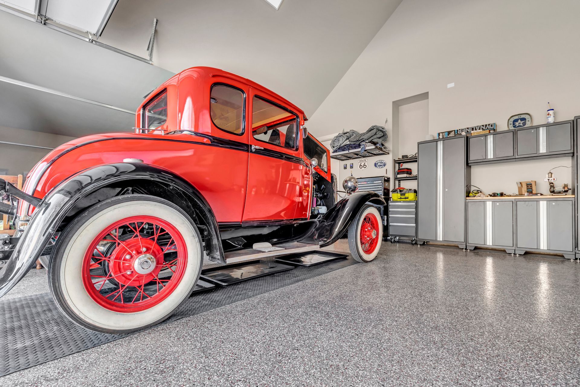 Red vintage car in a bright garage with polished floor and shelves along the wall