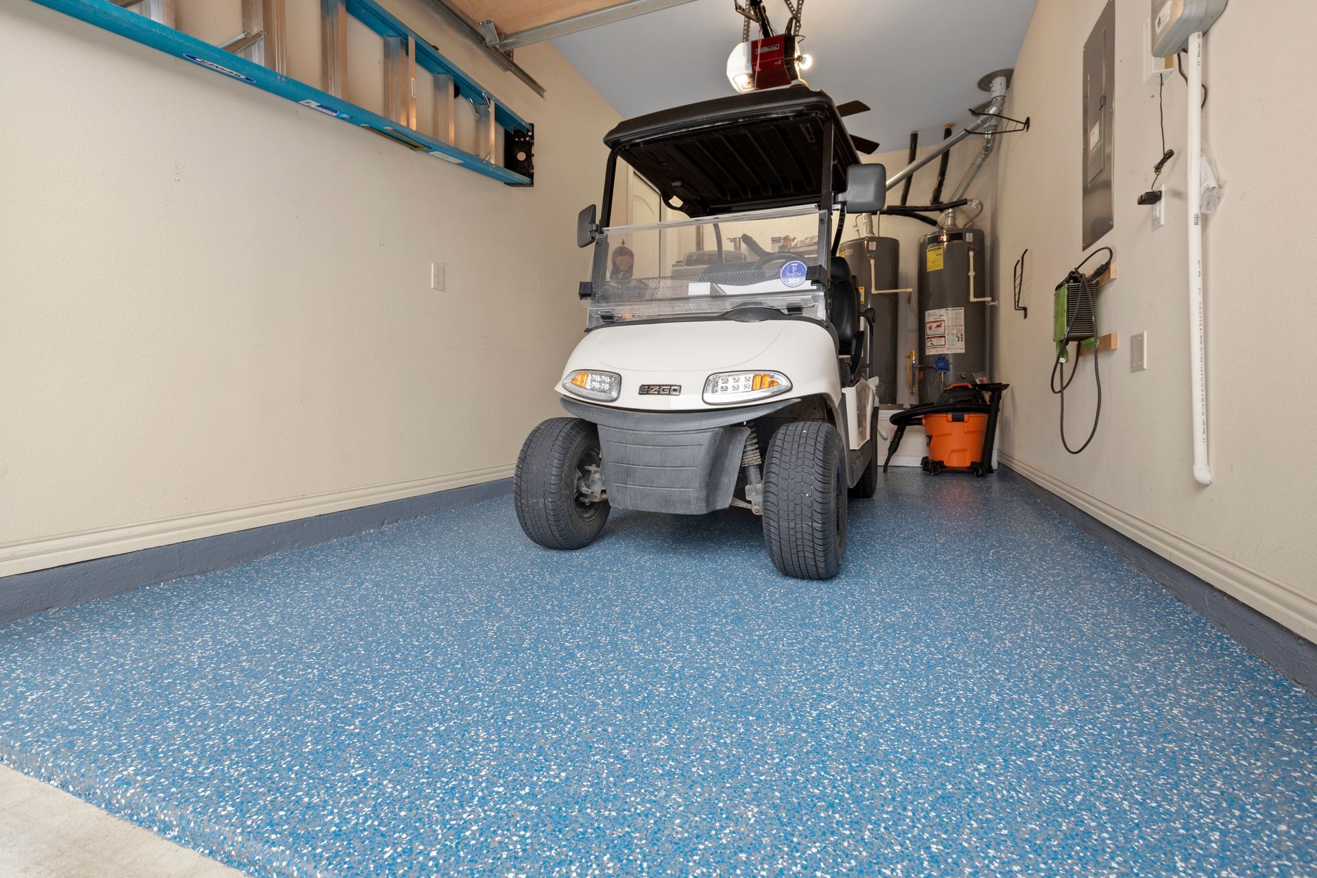 Small white utility cart parked in a garage with a speckled blue floor and wall-mounted storage racks