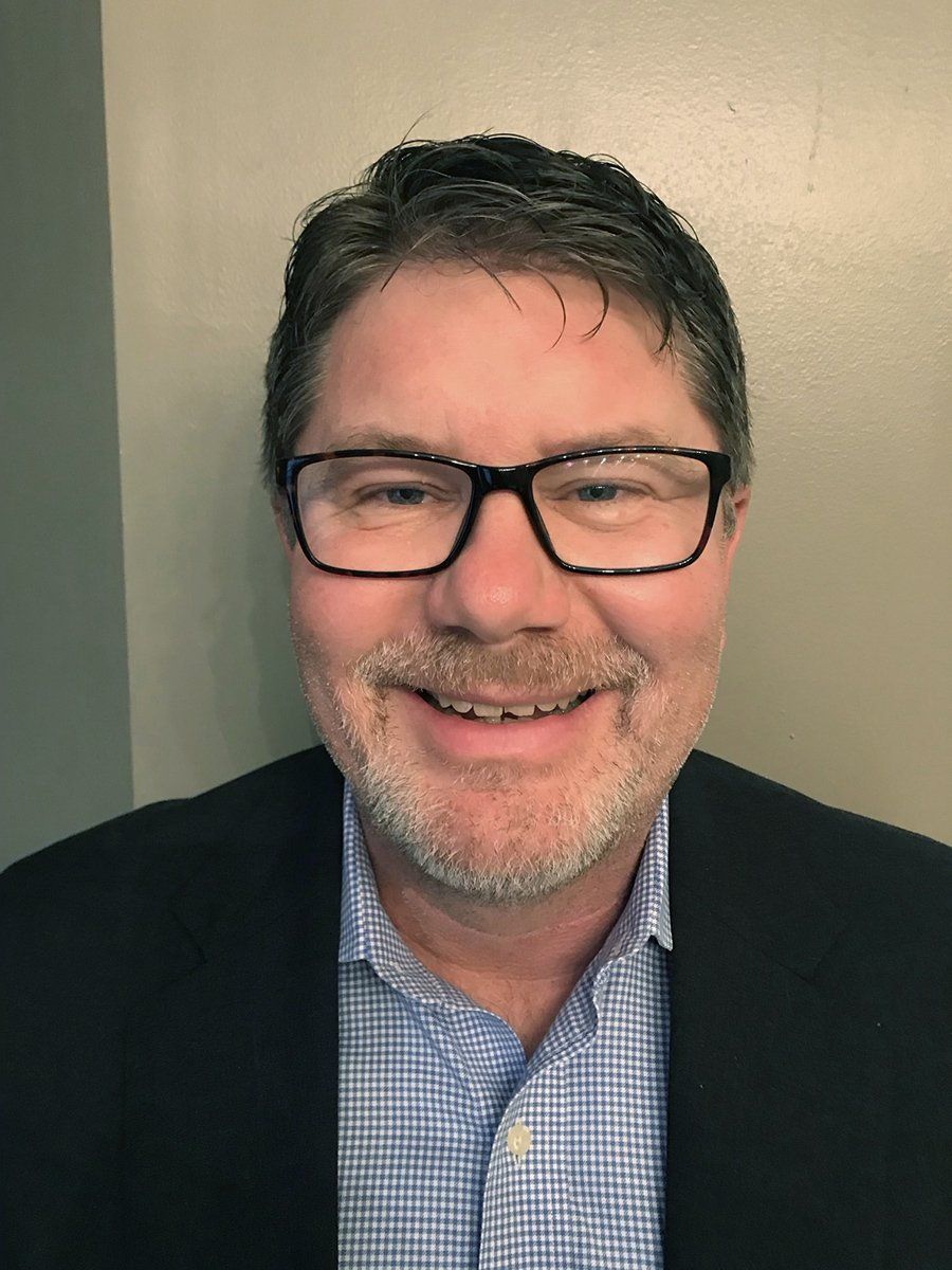 A man with glasses and a beard is smiling for the camera.