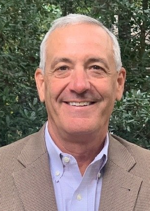 A man in a suit and blue shirt is smiling for the camera.