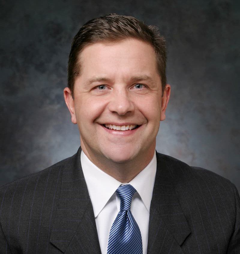 A man in a suit and tie smiles for the camera