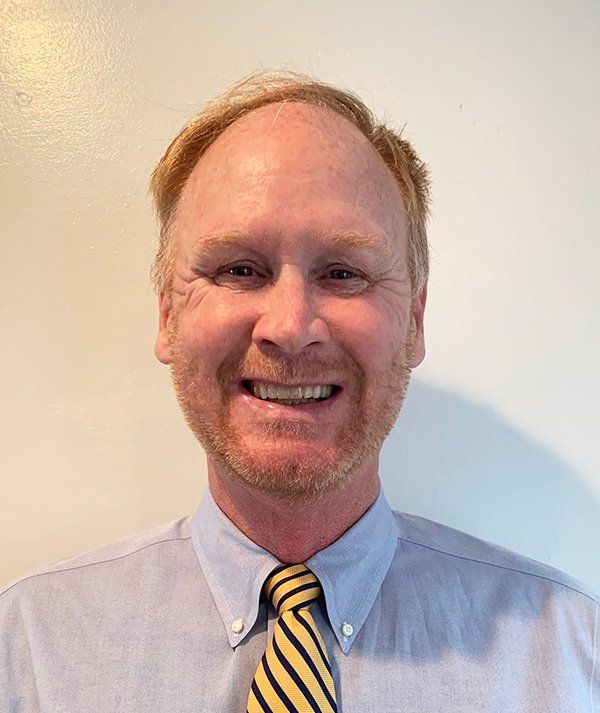 A man wearing a shirt and tie is smiling for the camera.