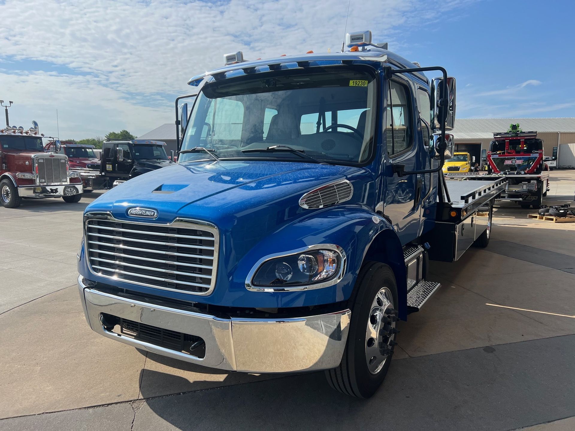 a blue freightliner tow truck is parked in a parking lot