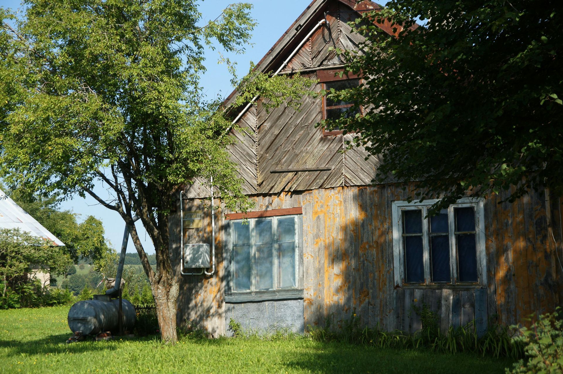 An old wooden house with a tree in front of it.