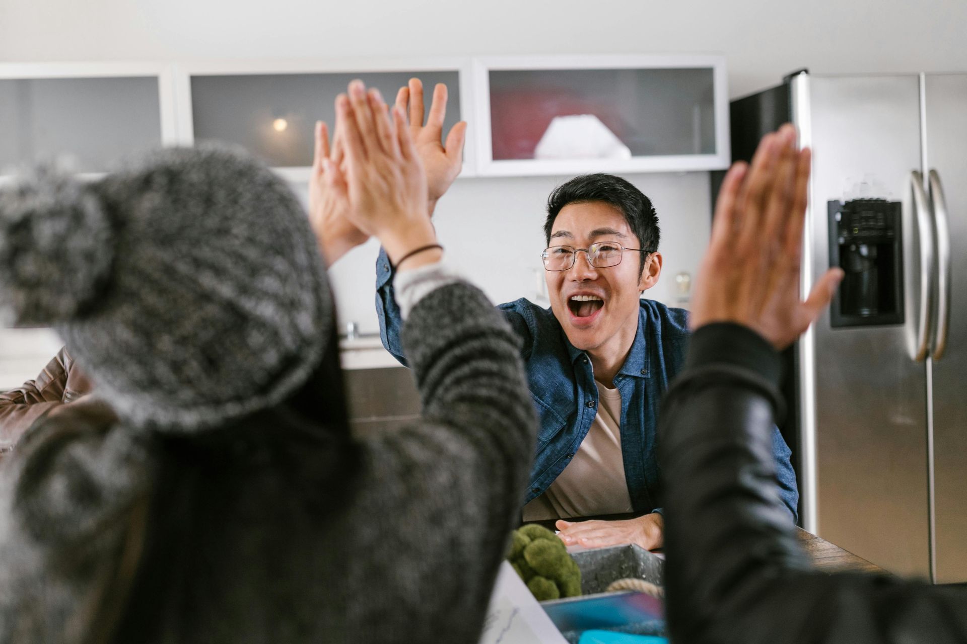 A group of people are giving each other a high five in a kitchen.