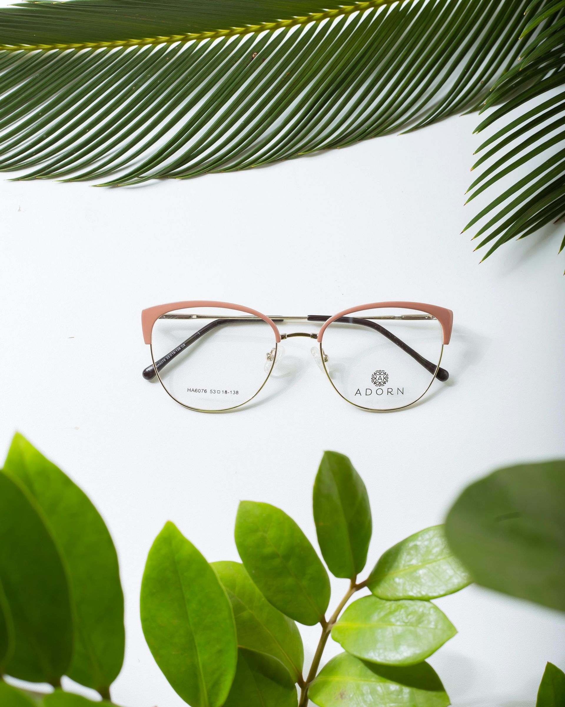 A pair of glasses sitting on top of a palm tree leaf.