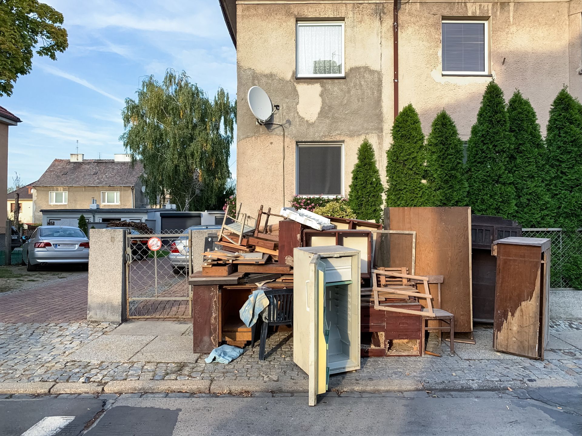 Pile of discarded furniture and debris on a sidewalk in front of a building.