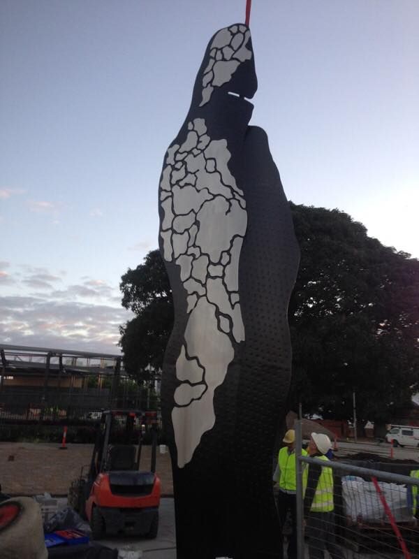 A large black and white statue with a forklift in the background