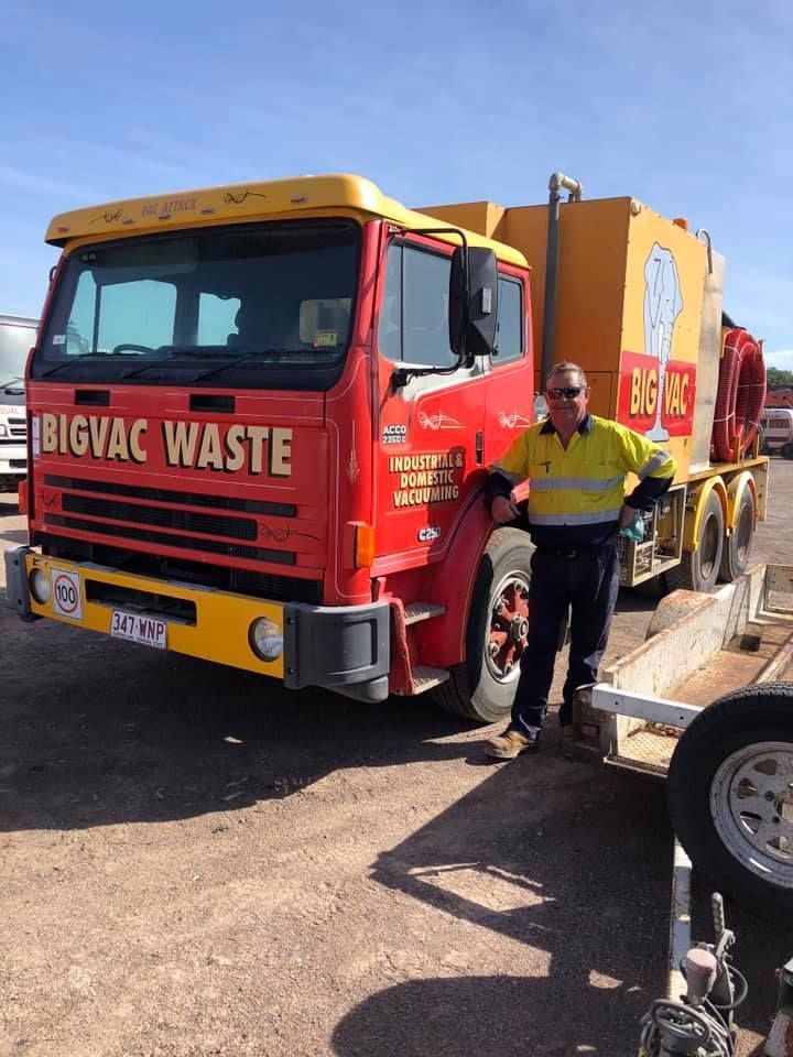 A man is standing in front of a bigvac waste truck