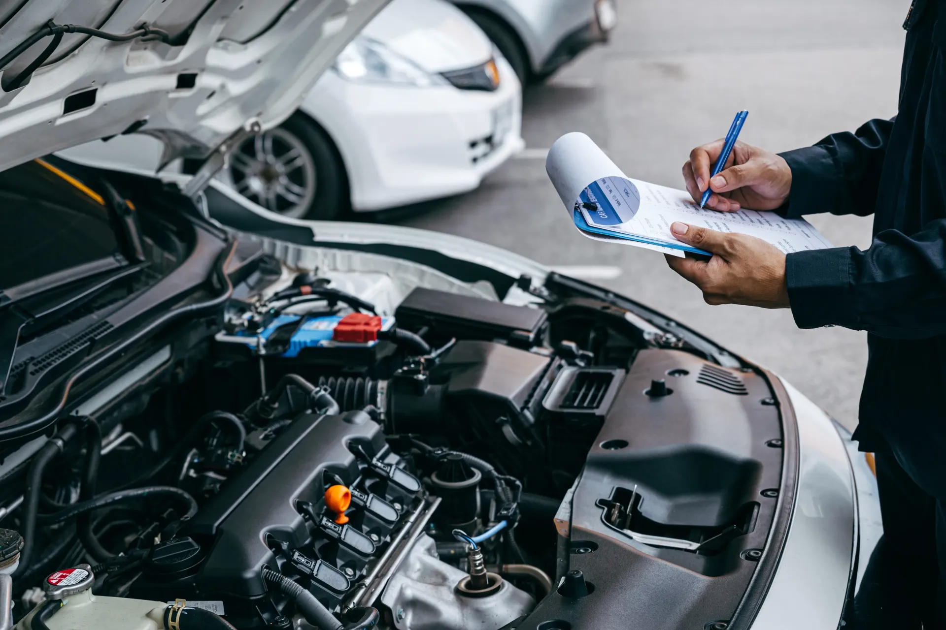 Mechanic inspecting car engine with clipboard in a service bay.  — Bob Best Mechanical in Drayton, QLD