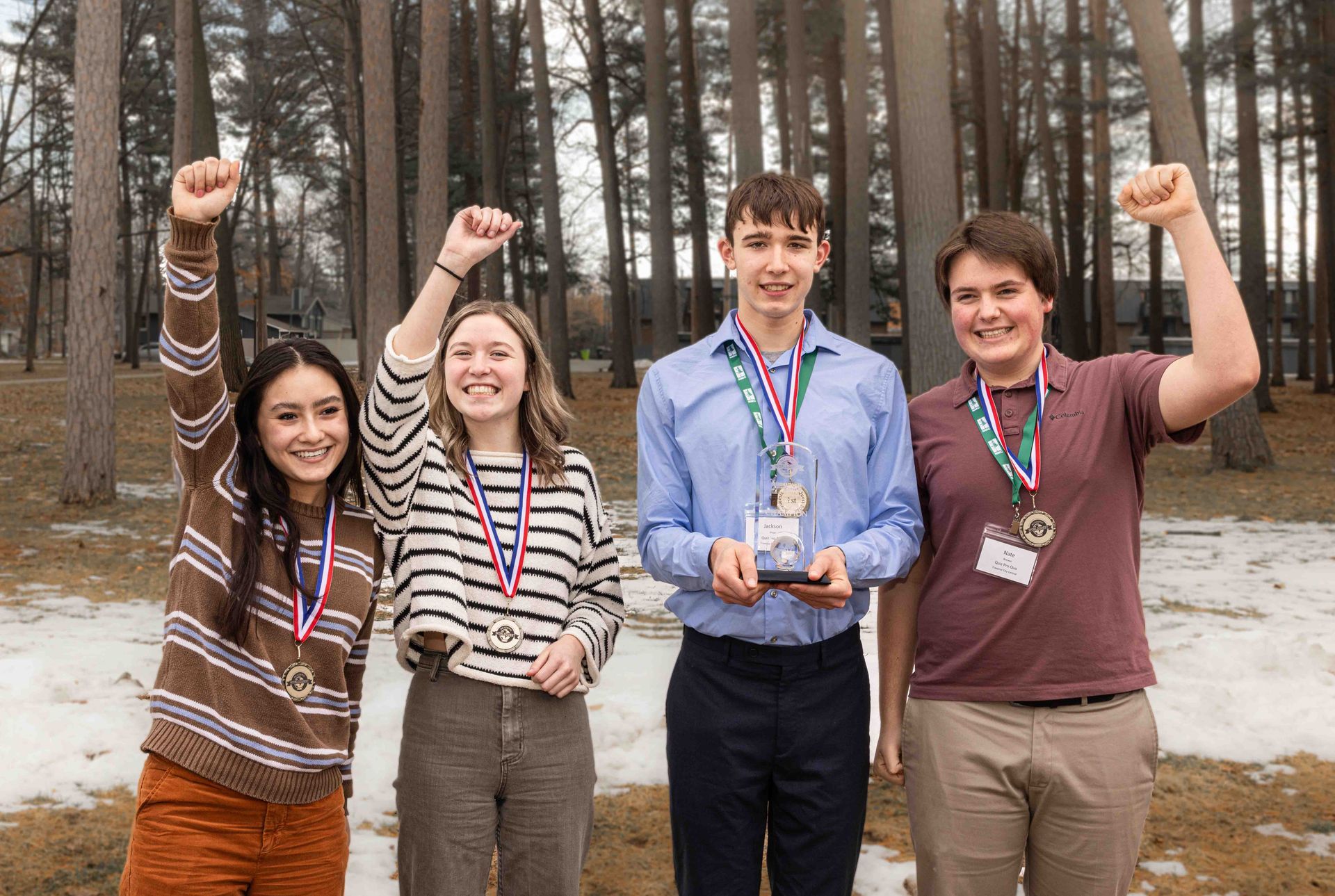 A group of young people standing next to each other with their arms in the air.