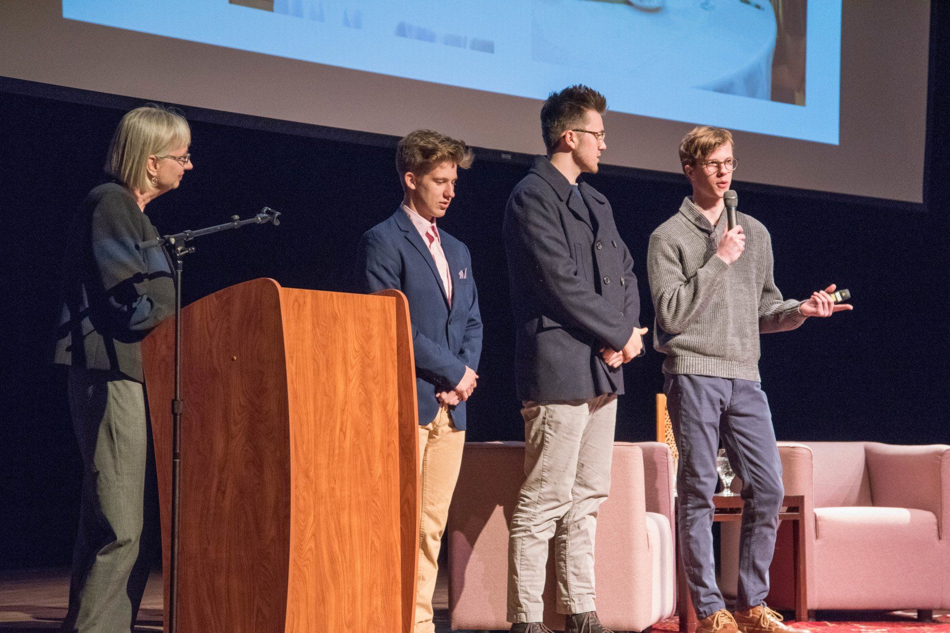 A group of people are standing in front of a podium on a stage.