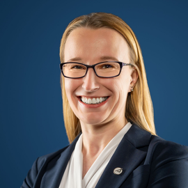 Group of people standing outside on a path, with trees in the background. Some are smiling.