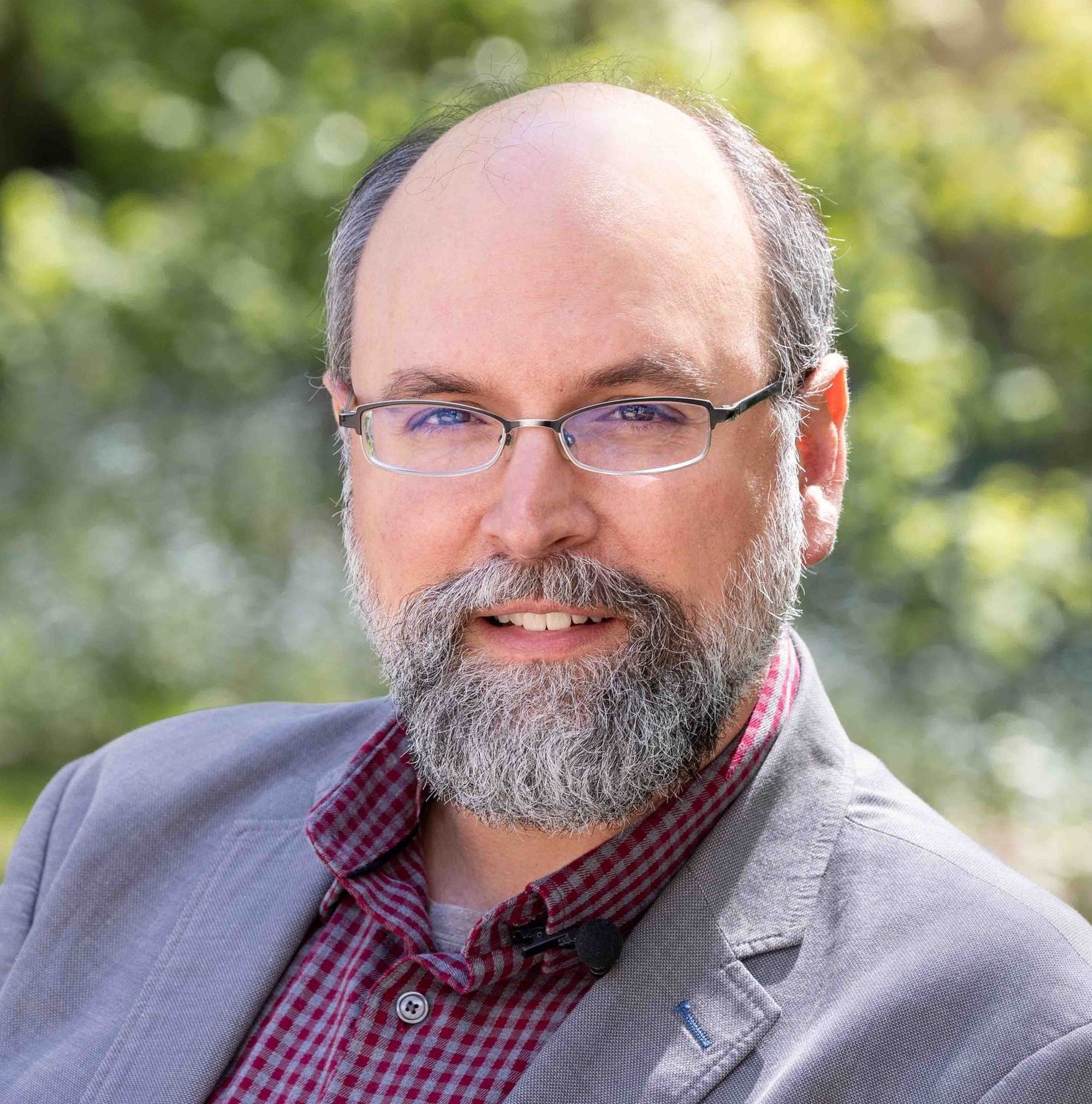 A bald man with a beard and glasses is smiling for the camera.