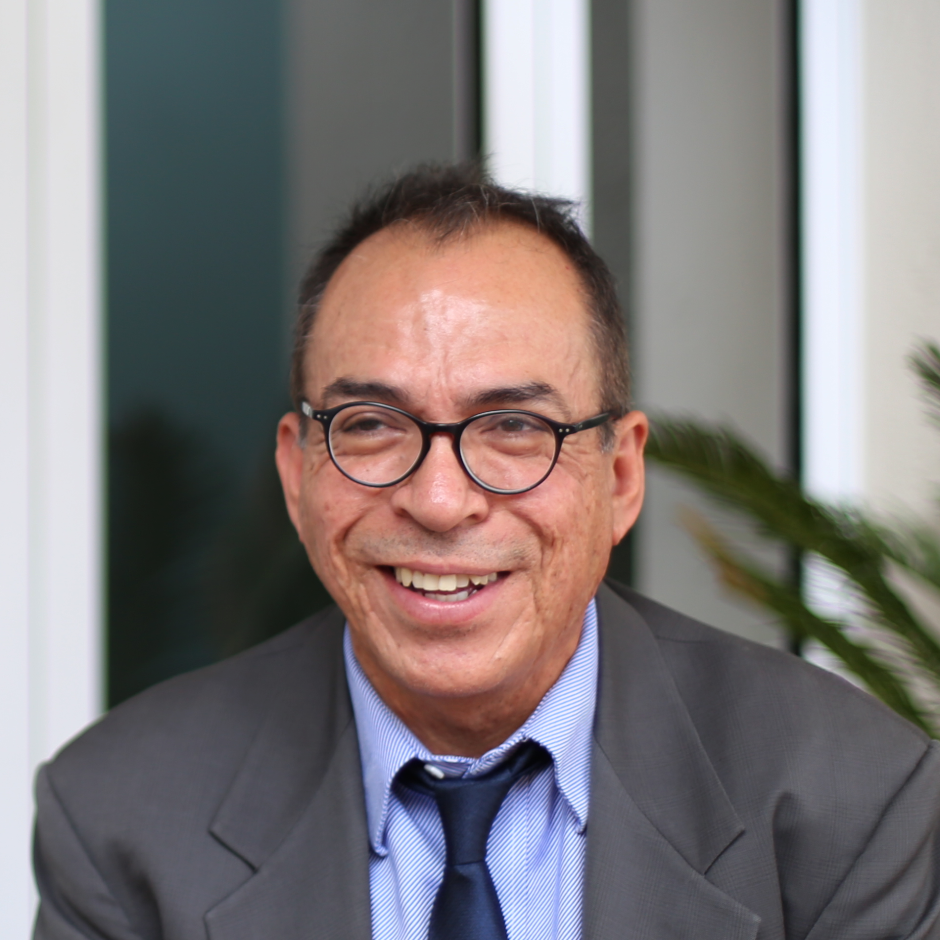 A man in a suit and tie is smiling and wearing glasses.