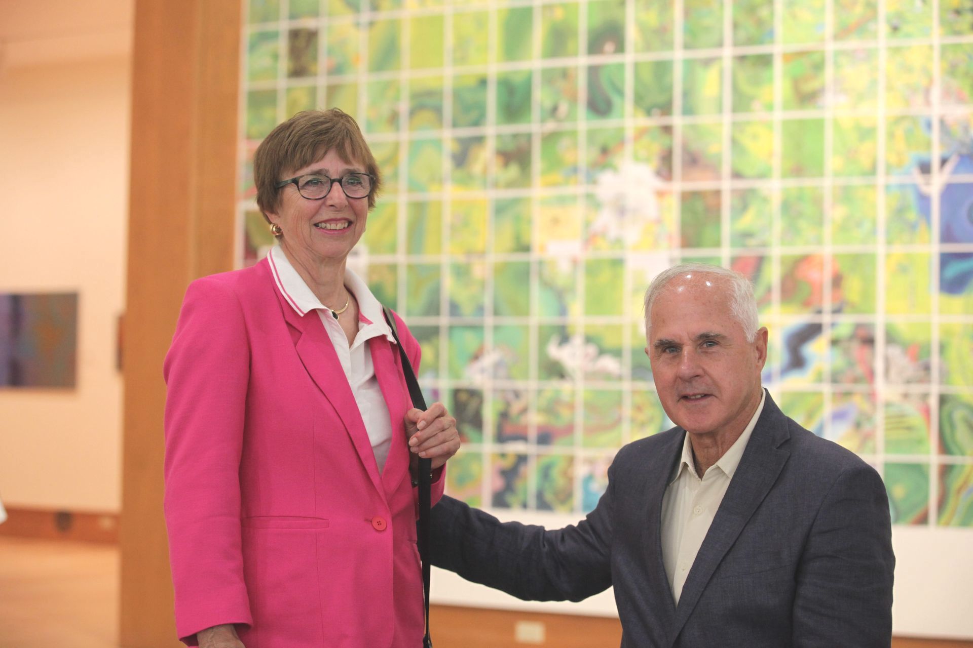 A man and a woman are standing next to each other in front of a painting.