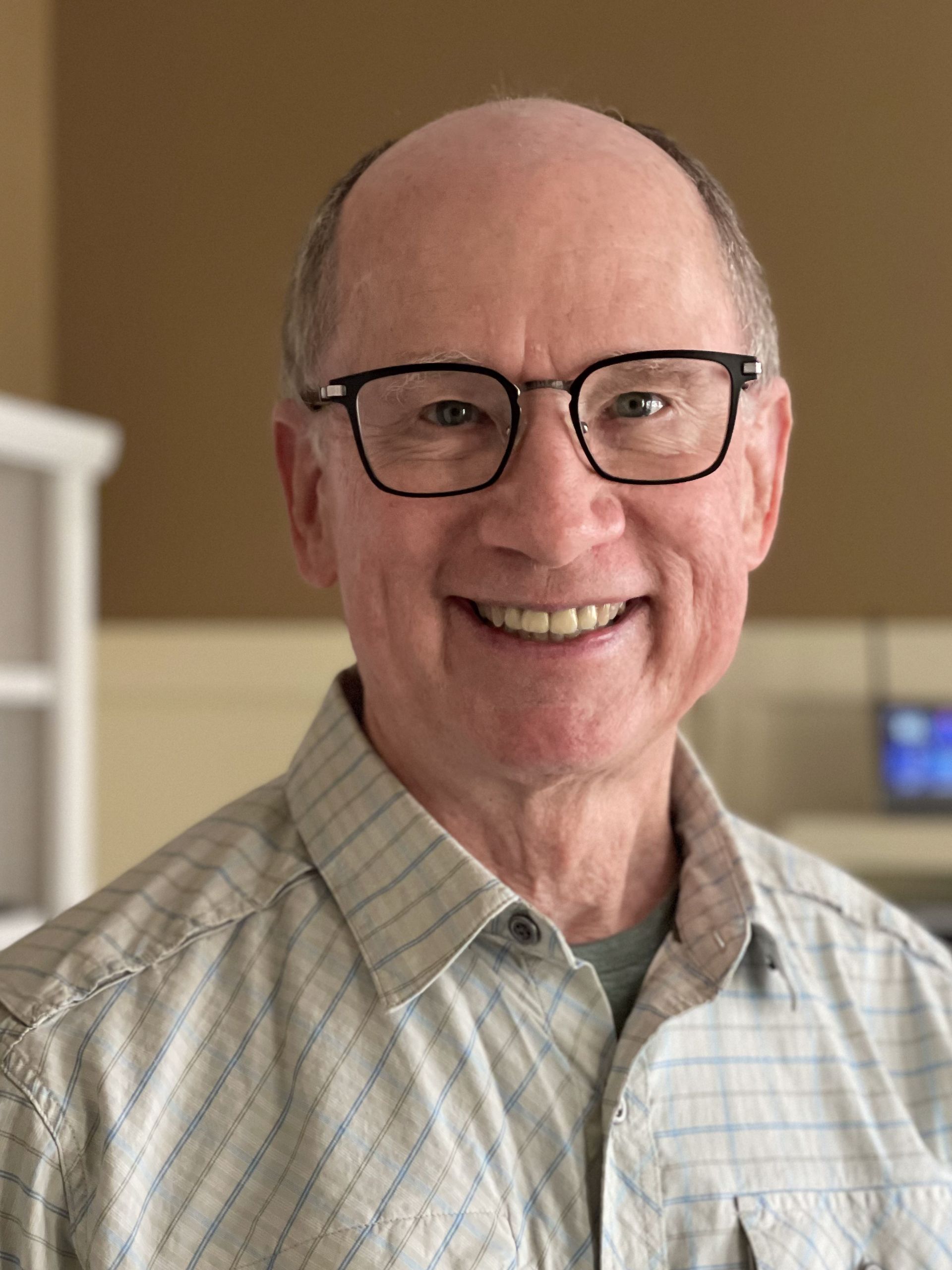 Ed Ketterer, a man wearing glasses and a plaid shirt smiles for the camera