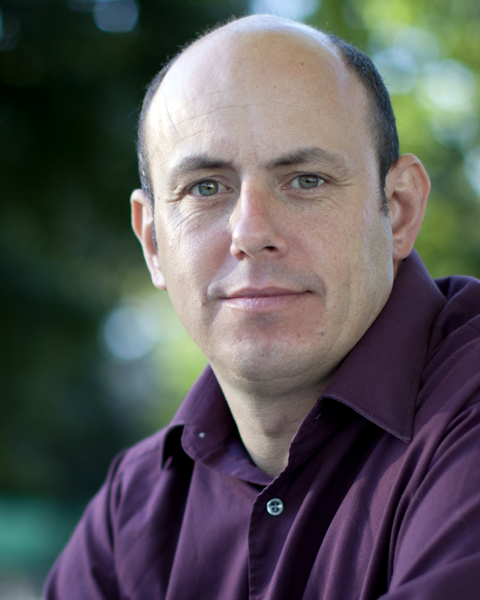 Ed Ketterer, a man wearing glasses and a plaid shirt smiles for the camera