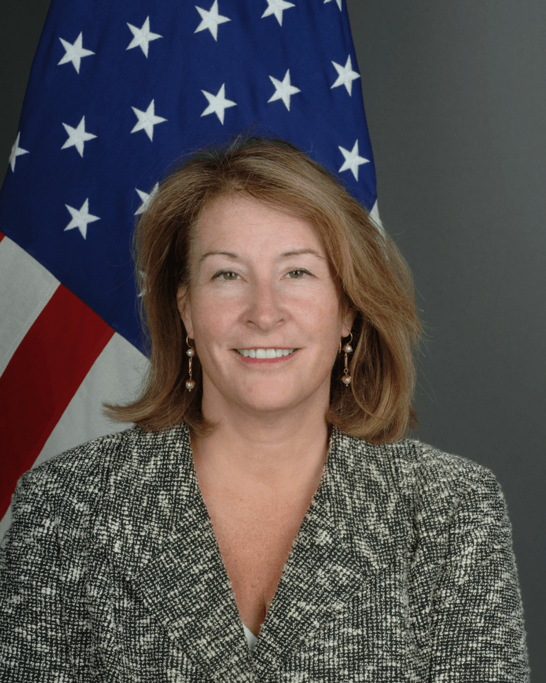 A woman is smiling in front of an american flag