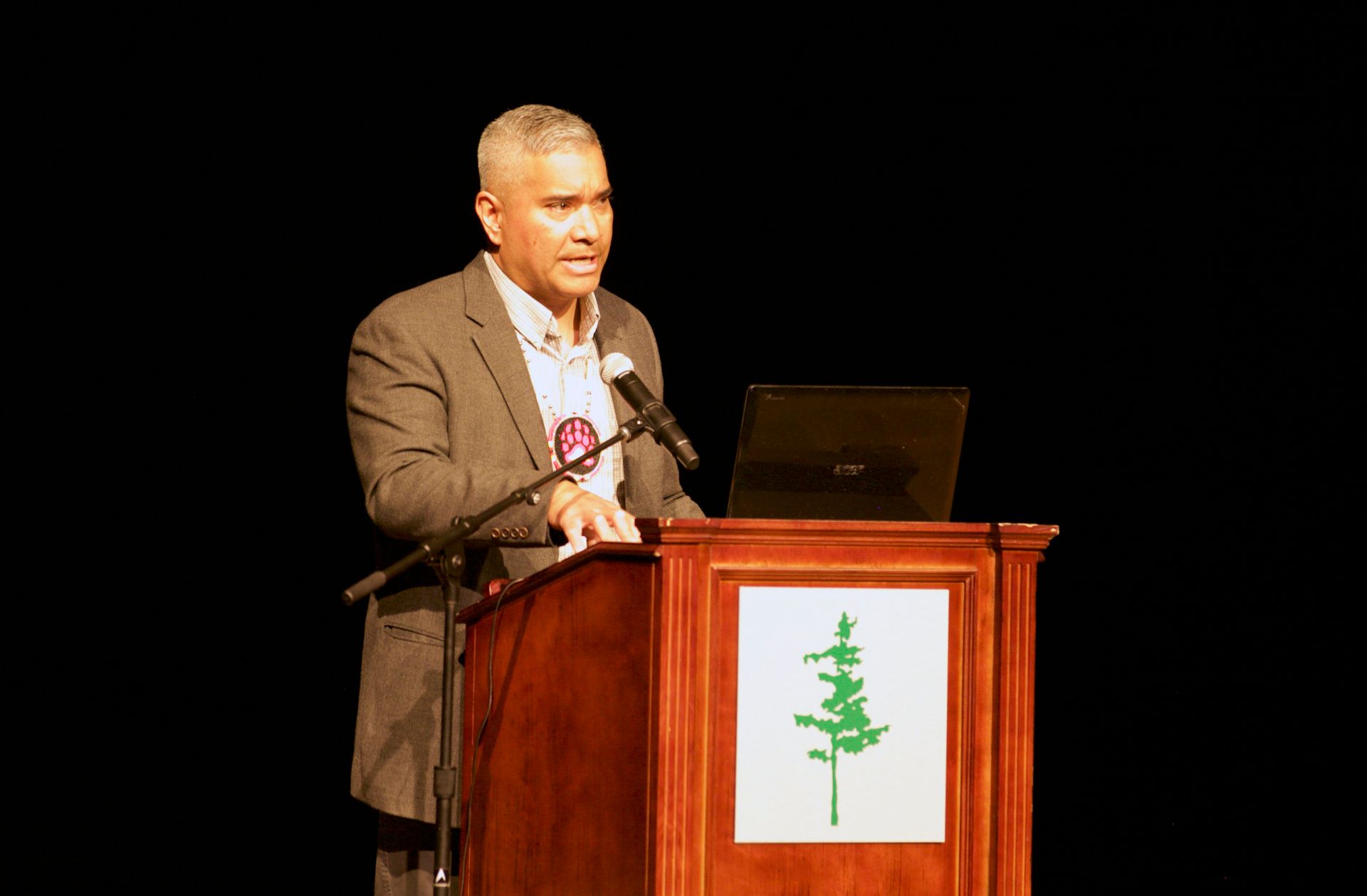 A man is standing at a podium speaking into a microphone.