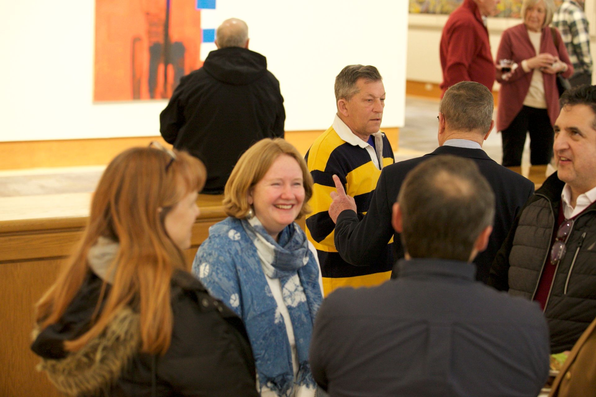 A group of people are standing in a room talking to each other