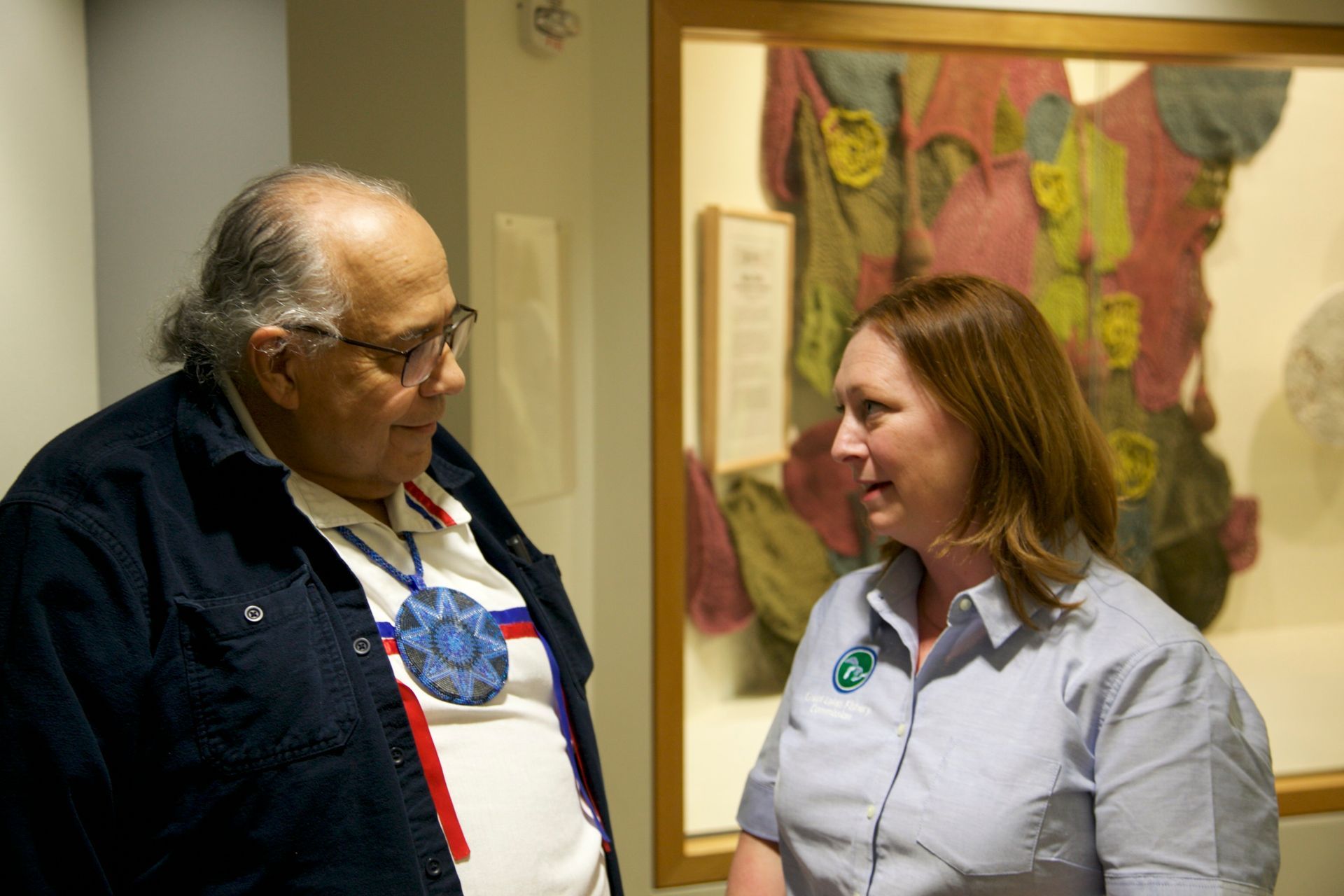 A man and a woman are standing next to each other in front of a painting.