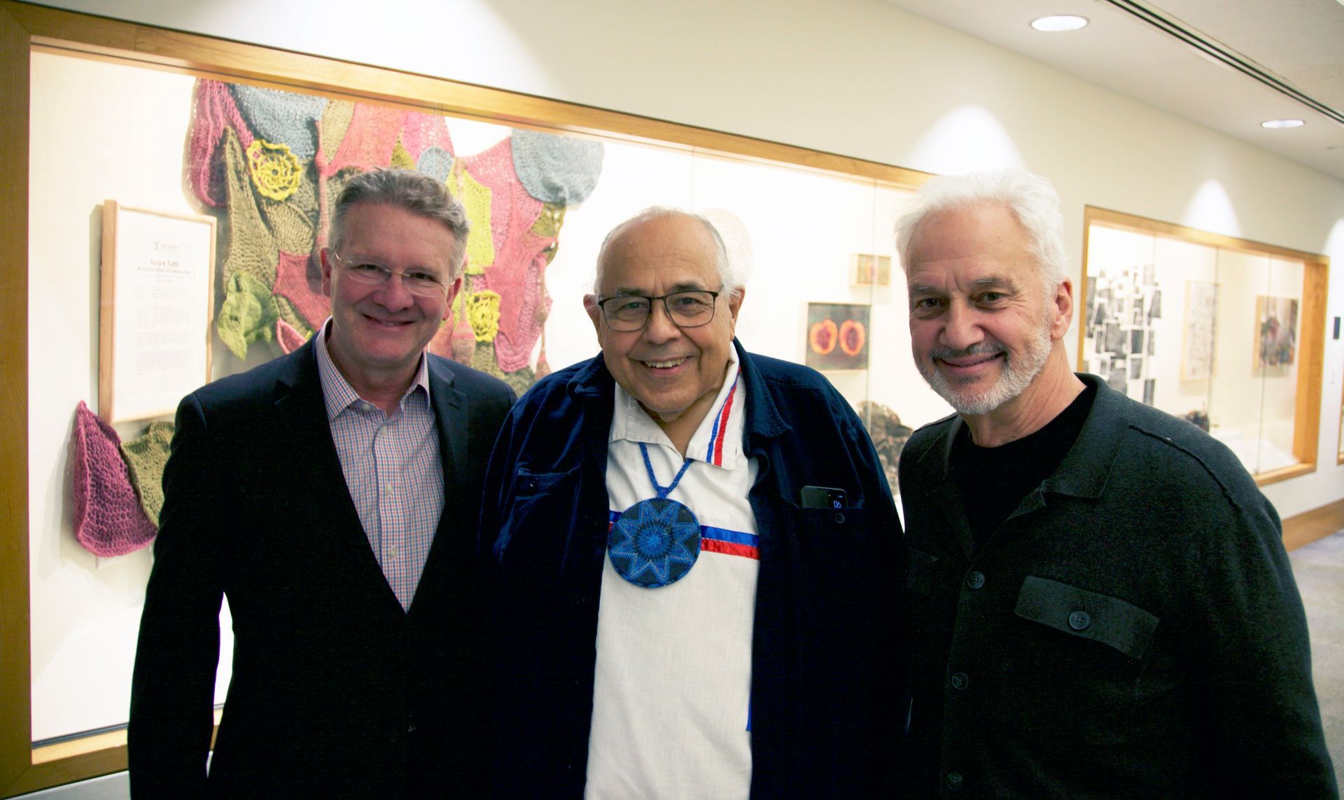 Three men are posing for a picture in a hallway.