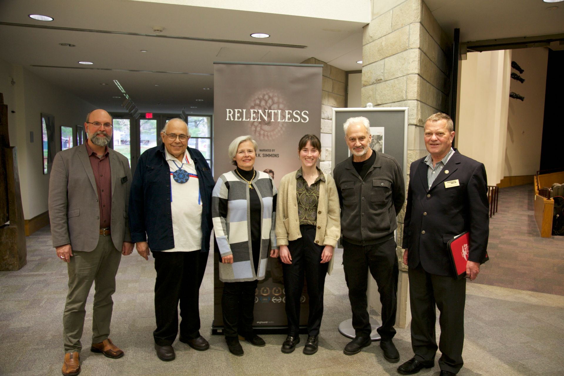 A group of people standing in front of a sign that says relentless.