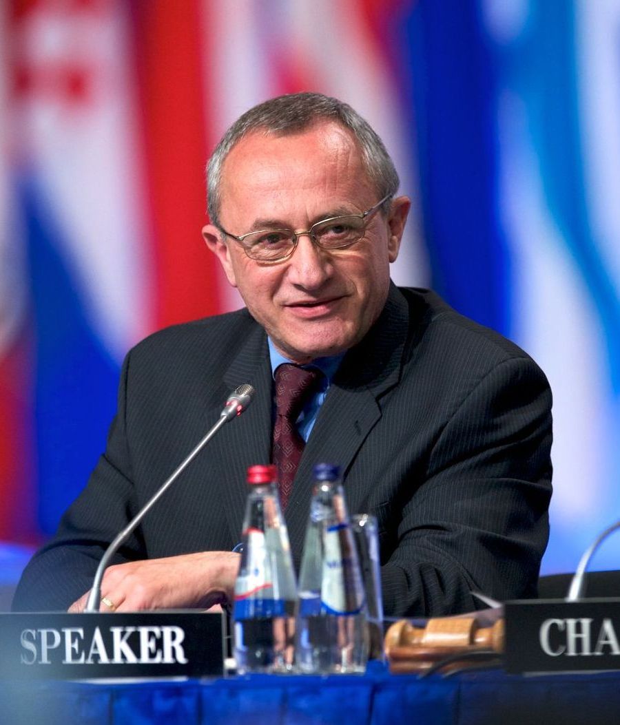 A man sitting at a table with a sign that says speaker