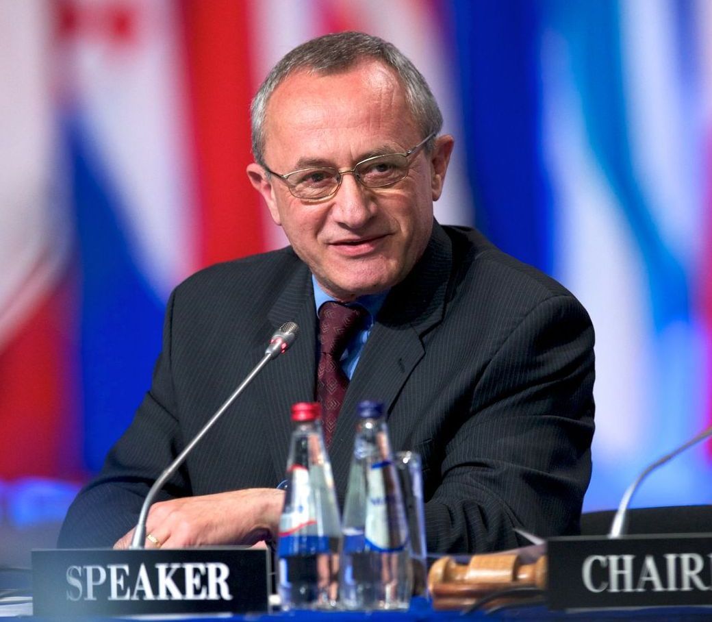 A man sitting at a table with a sign that says speaker