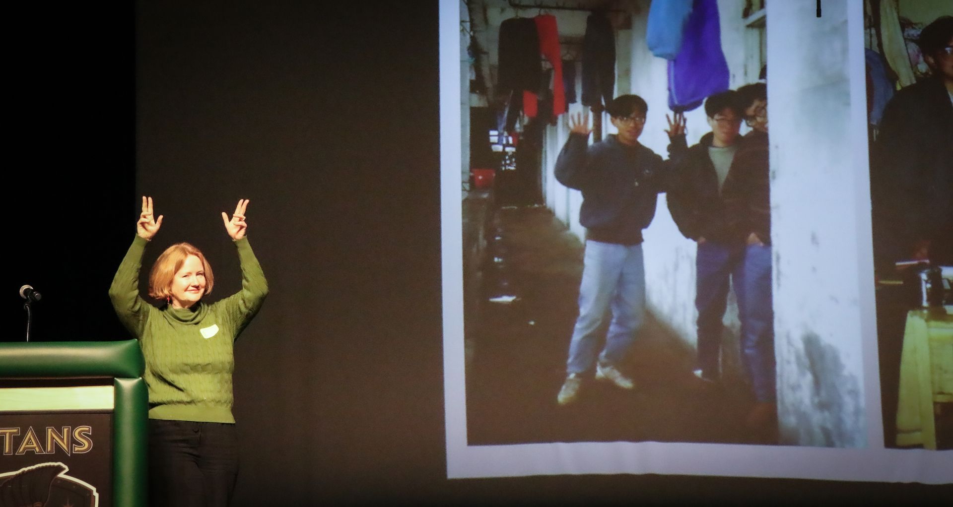 A woman stands in front of a projector screen that says mountains