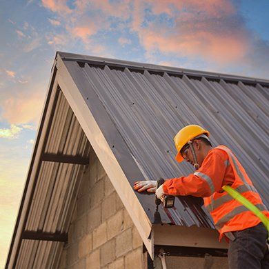 A man is working on a roof with a drill.