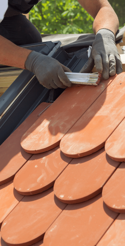 A man is laying tiles on a roof.