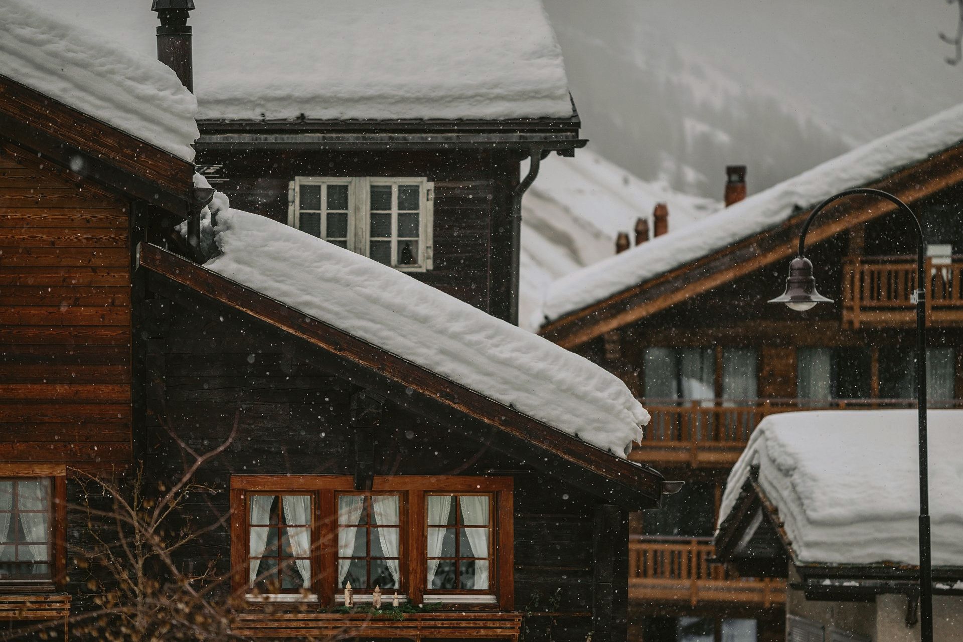 A snowy roof of a wooden house in the mountains.