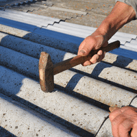 A person is holding a hammer over a roof.