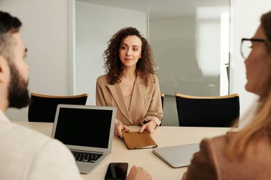 A woman is sitting at a table talking to a man and a woman.