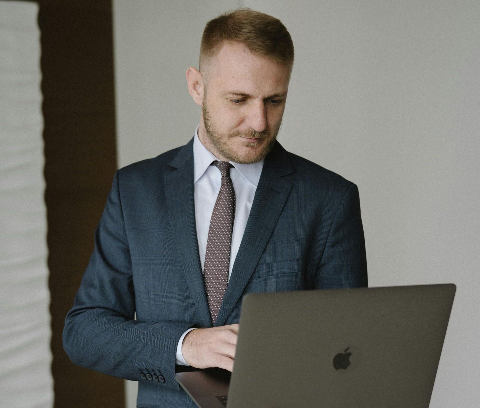 A man in a suit and tie is using an apple laptop