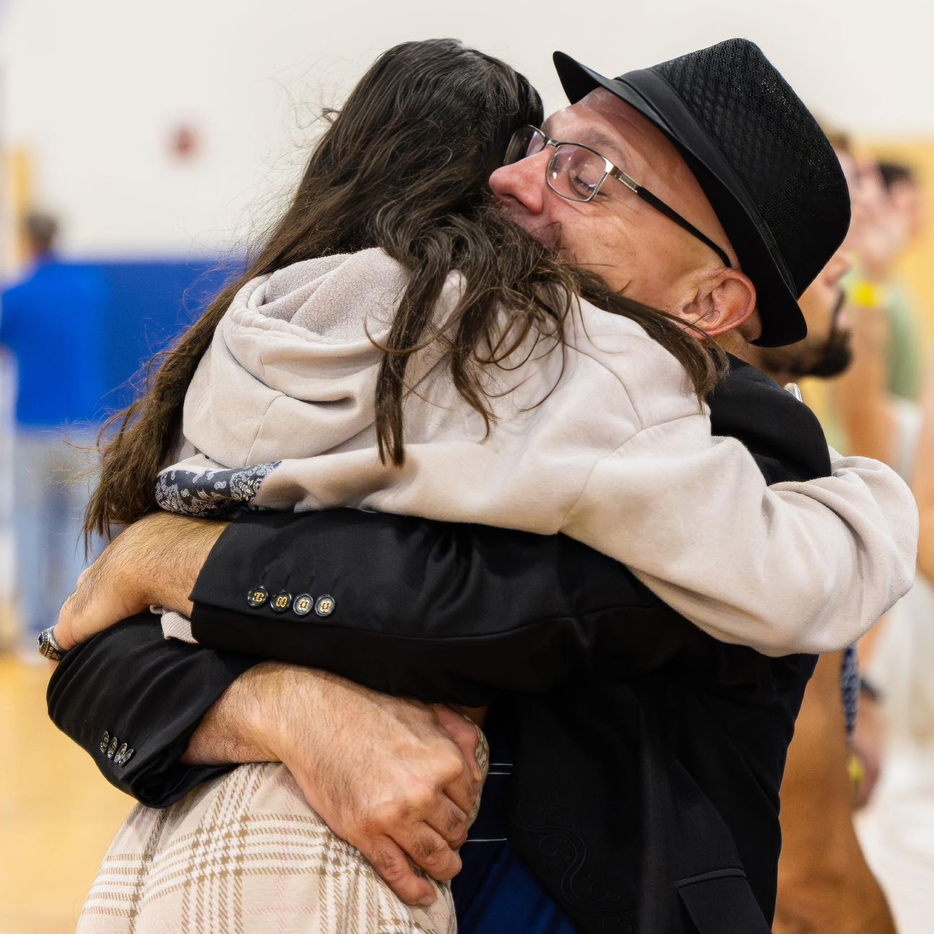 A man in a hat and glasses is hugging a little girl