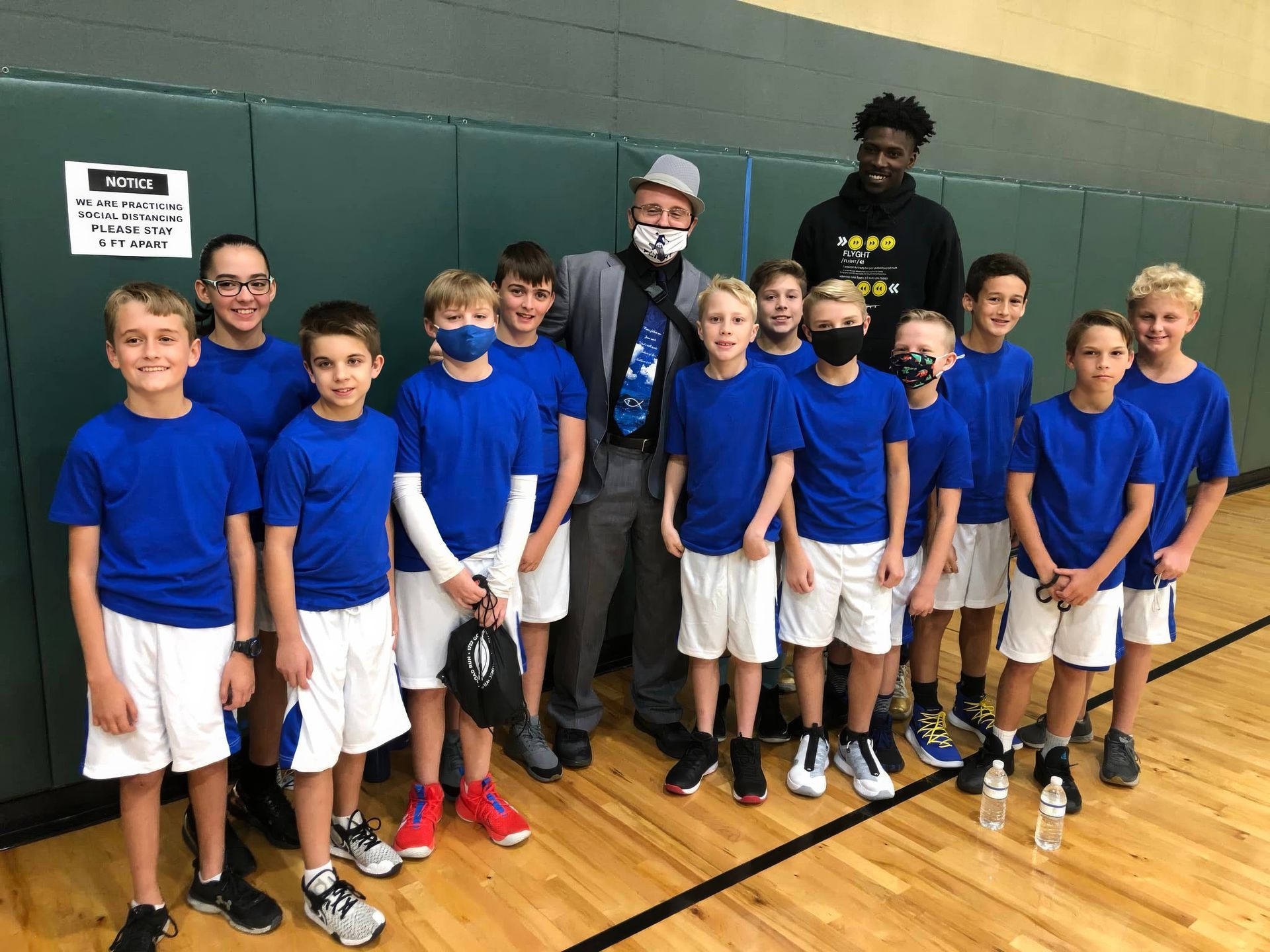 A man is holding up a trophy in front of a group of basketball players
