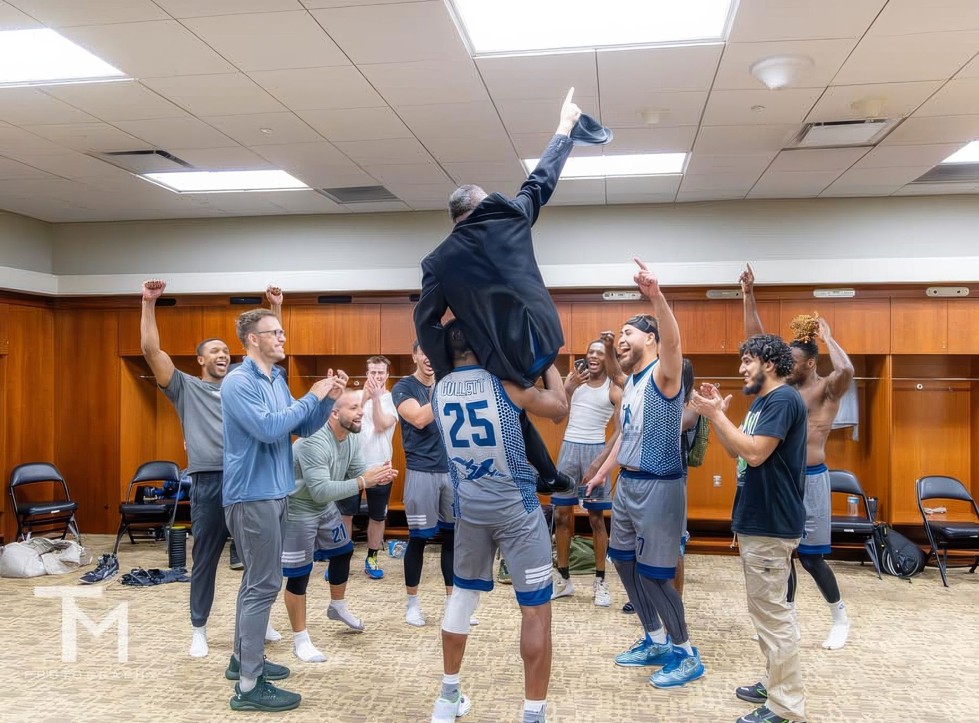 A group of basketball players are celebrating in a locker room.