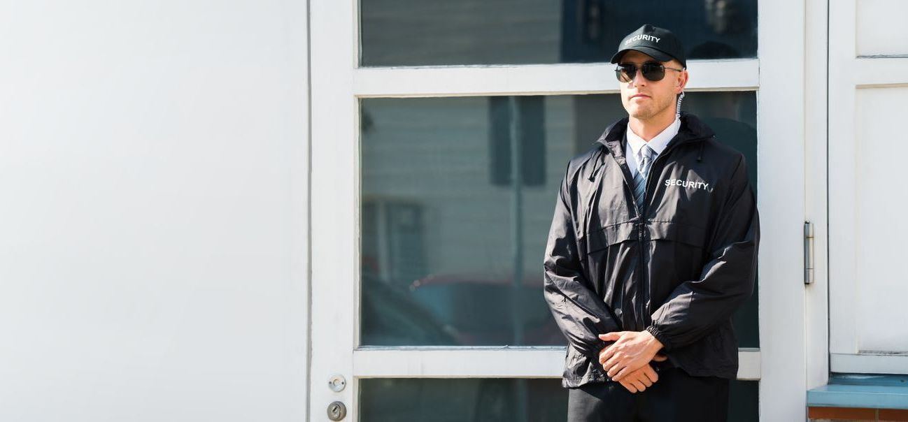 A security guard is standing in front of a door.