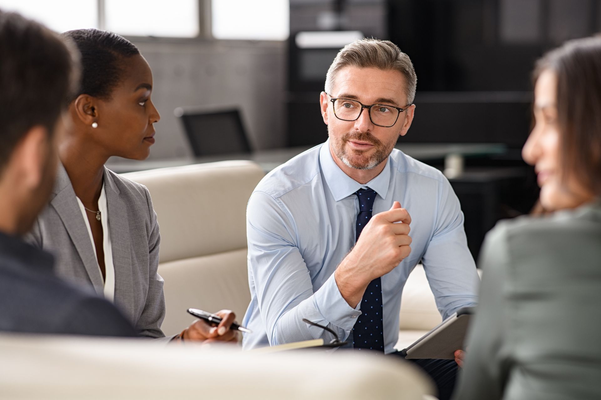 A group of business people are sitting around a table having a meeting.