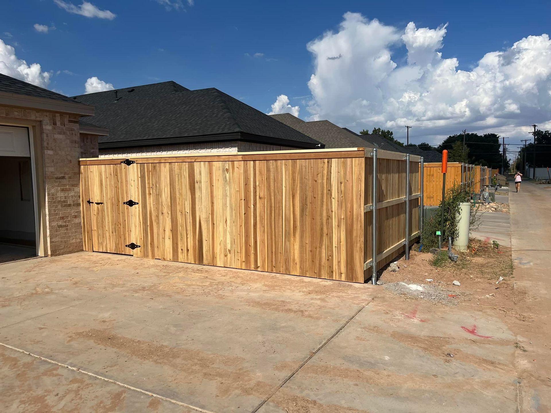 Wooden fence with a gate in front of a house on a sunny day.