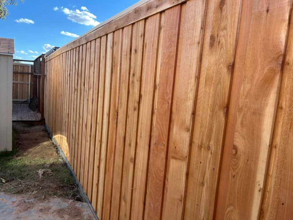 Wooden fence, cedar-toned, on a sunny day, with a blue sky.